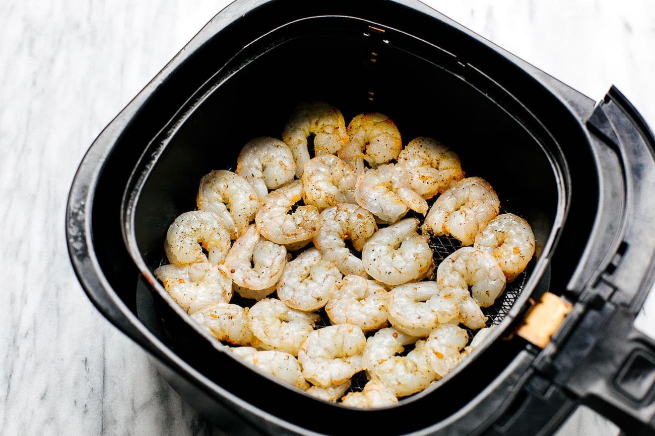 overhead view of basket air fryer containing raw shrimp