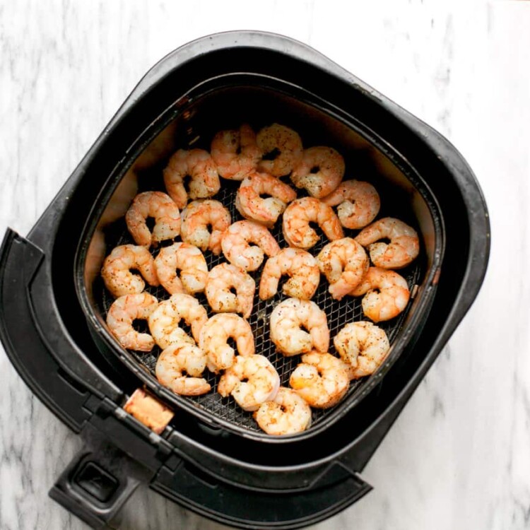 overhead view of basket air fryer containing cooked shrimp
