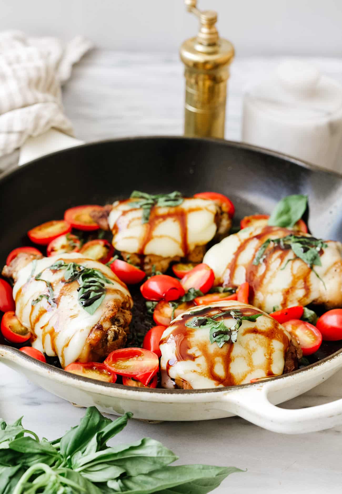 An angled view of a cast iron skillet with baked caprese chicken.