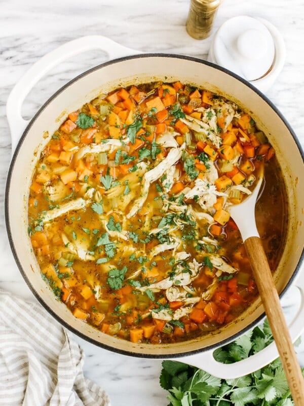 overhead view of sweet potato chicken soup in a white Dutch oven pot