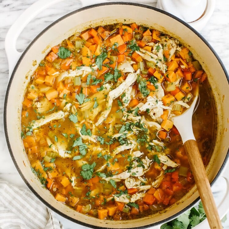 overhead view of sweet potato chicken soup in a white Dutch oven pot