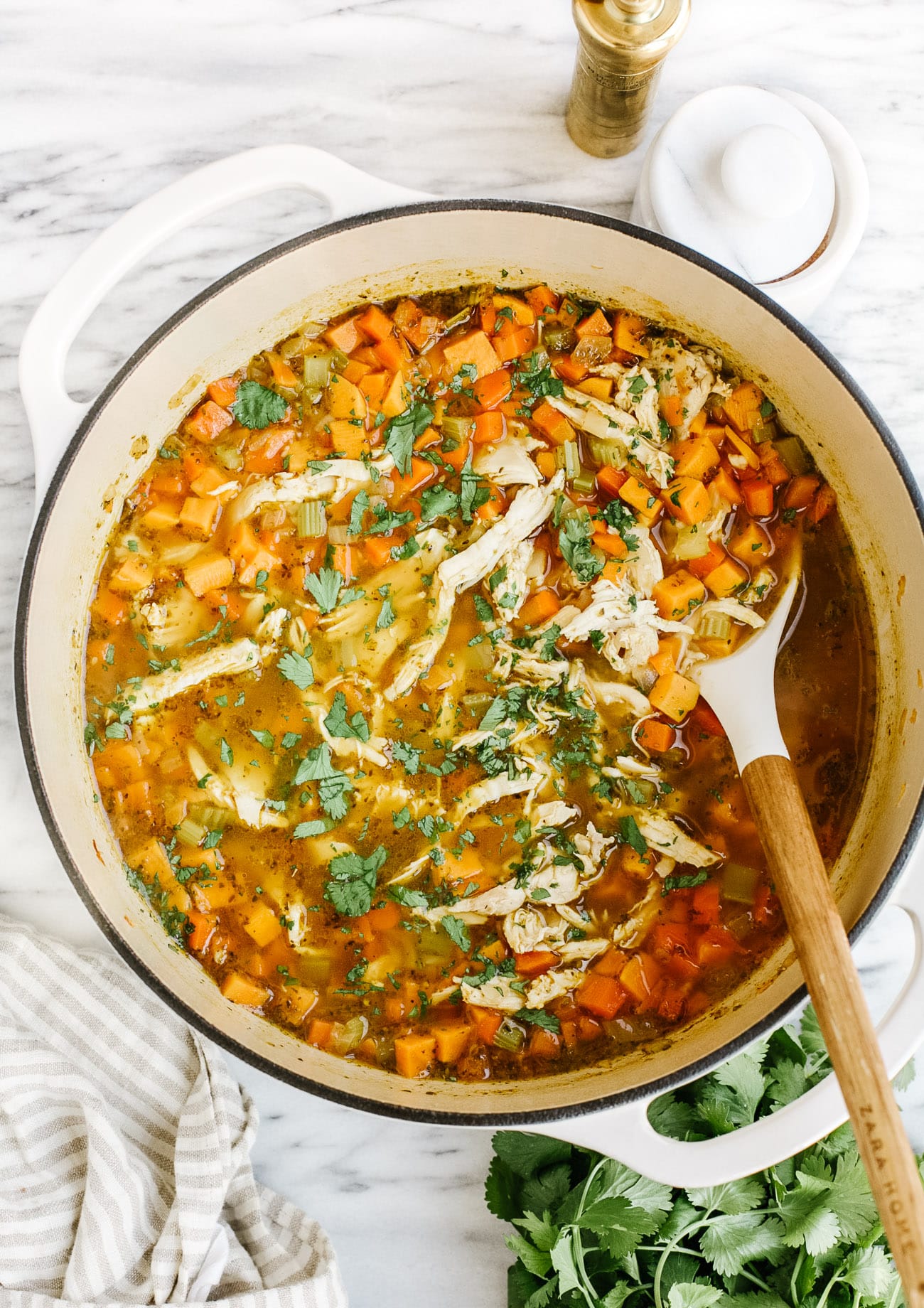 overhead view of sweet potato chicken soup in a white Dutch oven pot