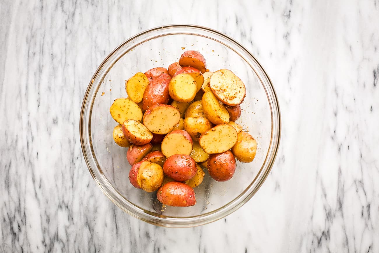 overhead view of seasoned baby potatoes in a glass bowl.