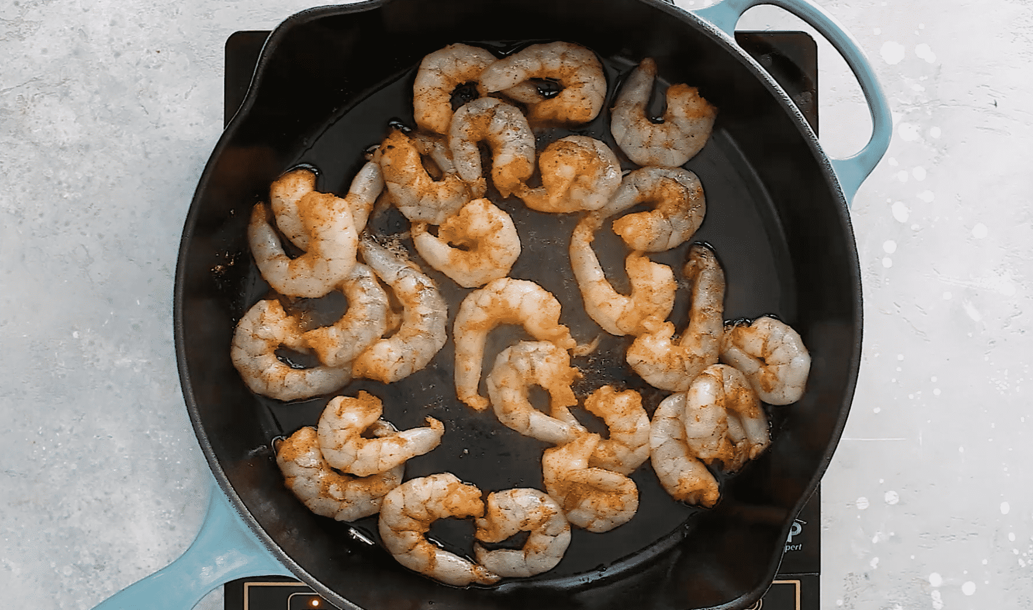 overhead view of cooked shrimp in a cast iron skillet. 
