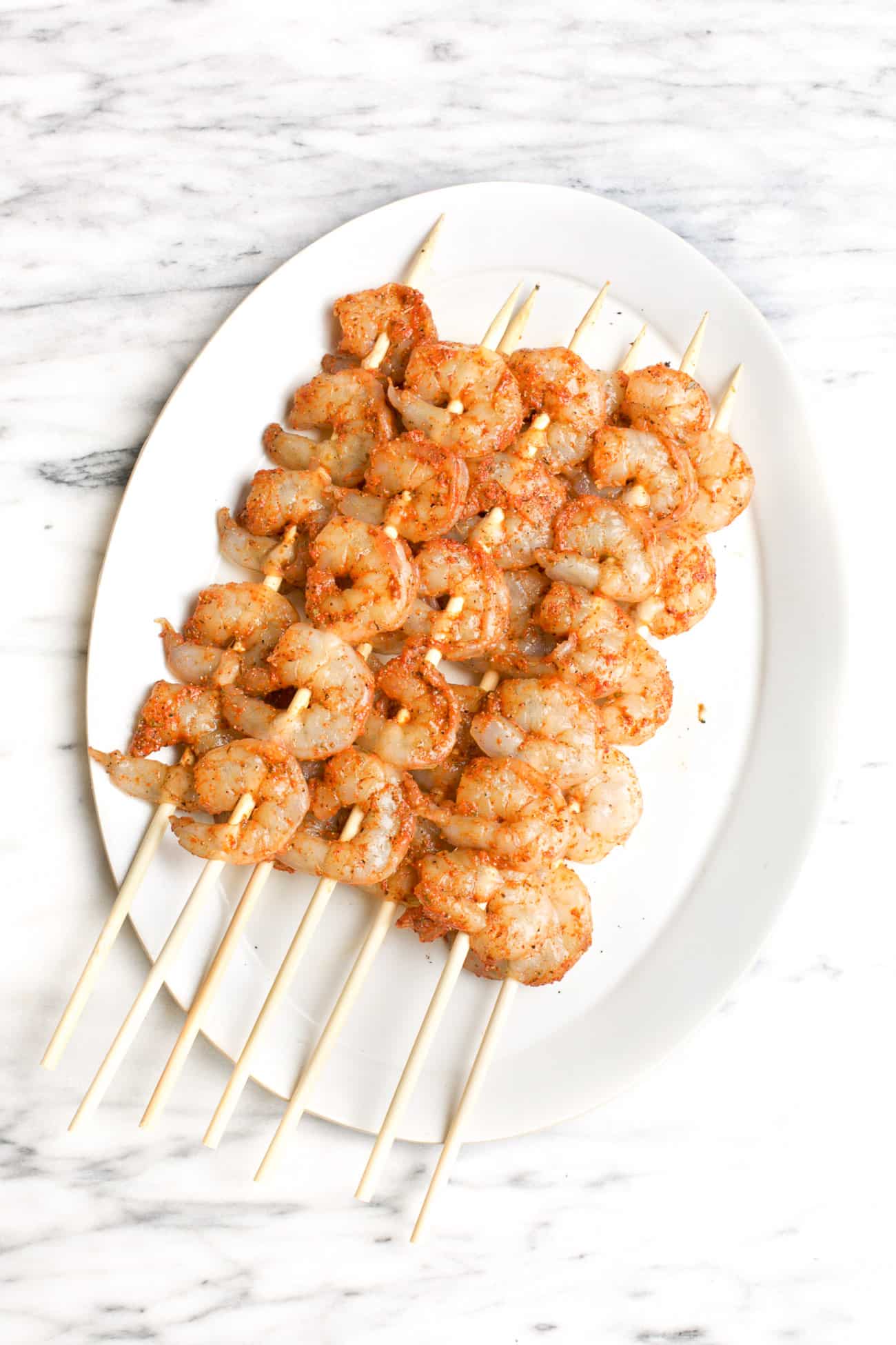 seasoned raw shrimp kabobs on a white plate