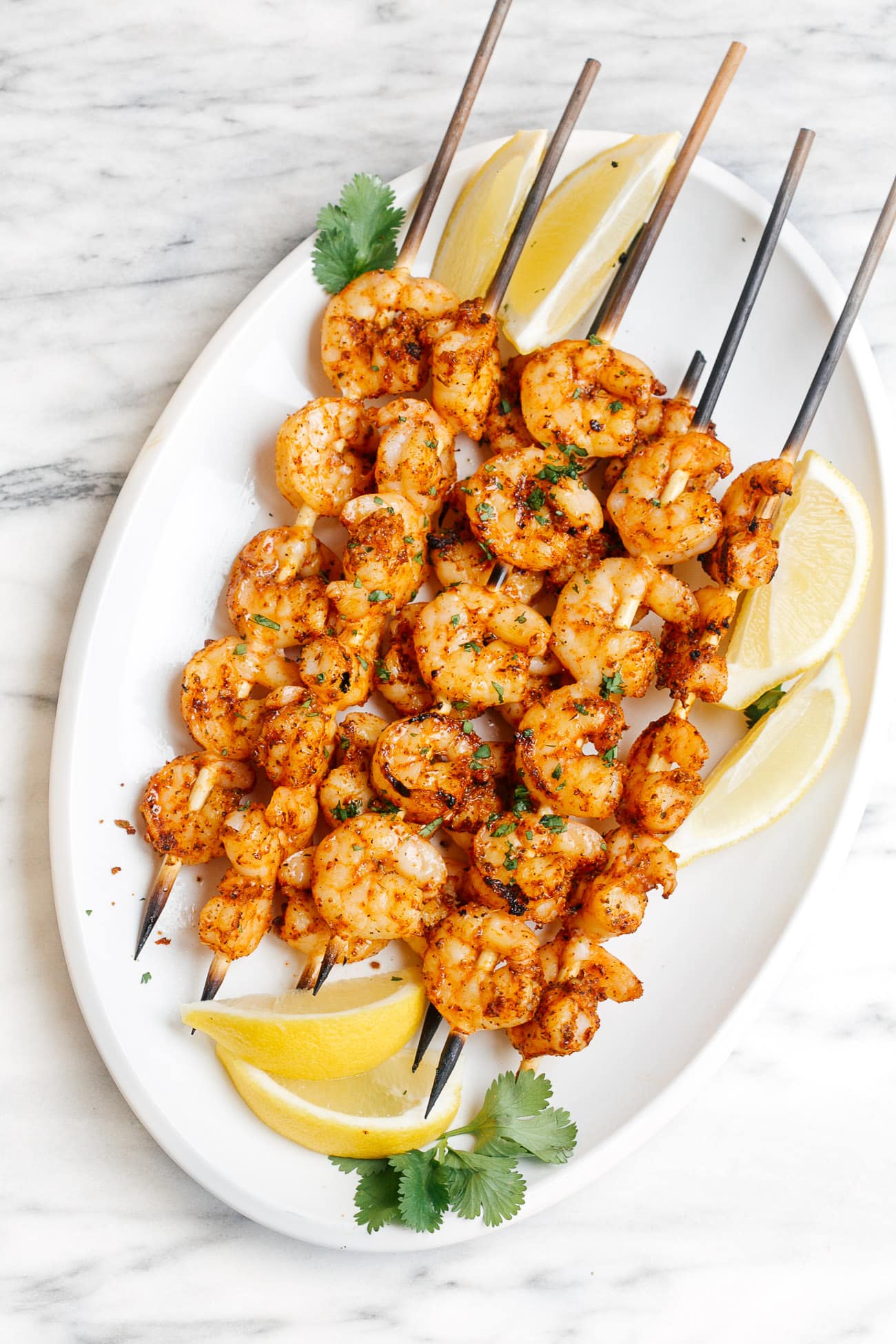 A platter with multiple cajun shrimp skewers. 