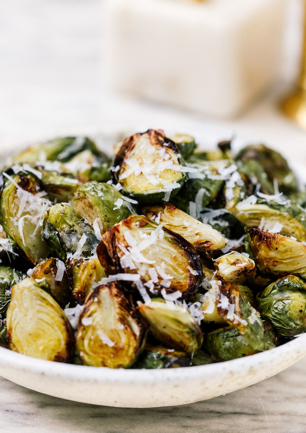 A serving bowl full of air fryer Brussels sprouts topped with parmesan cheese. 