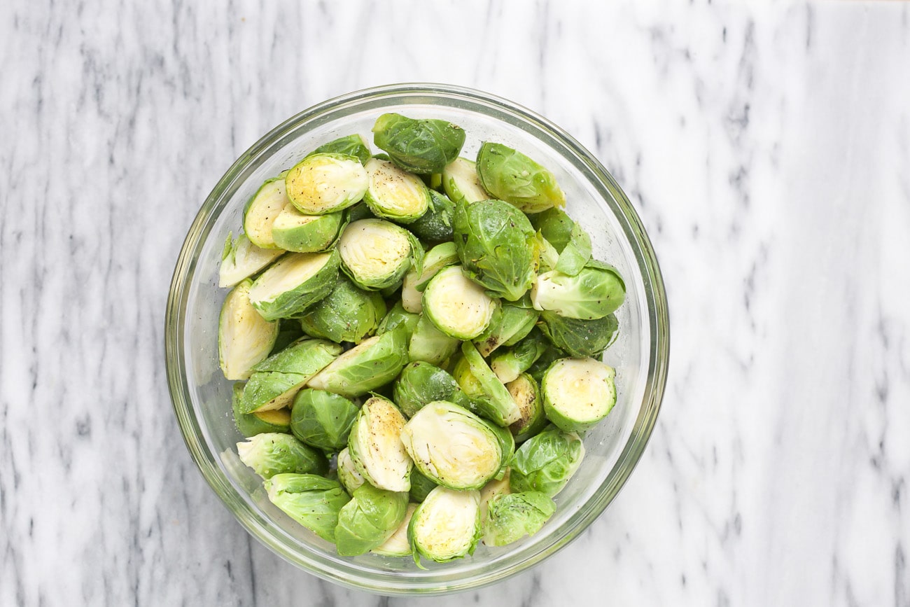Seasoned Brussels sprouts in a glass bowl. 