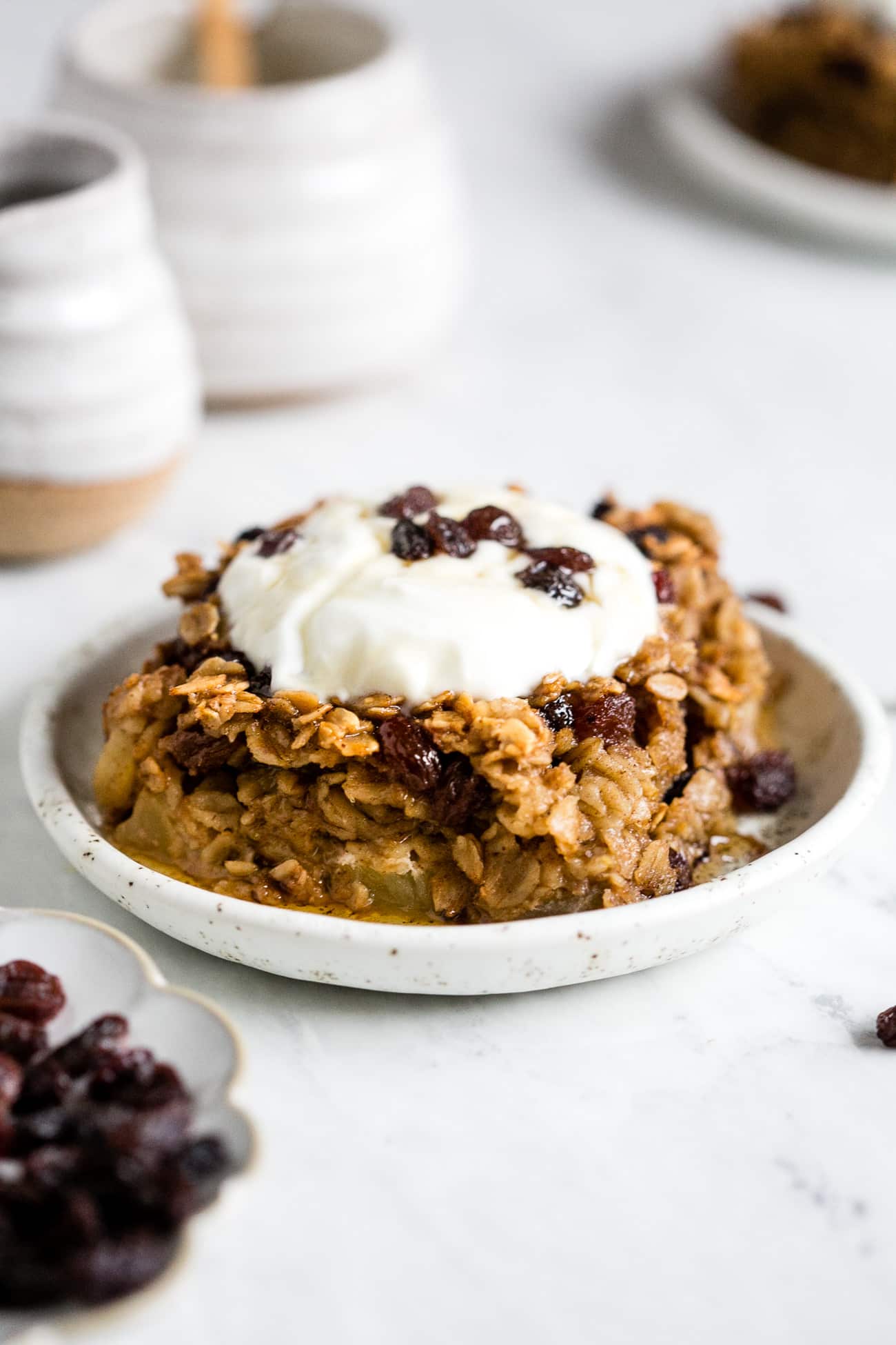 A piece of baked oatmeal with apples and raisins topped with yogurt.