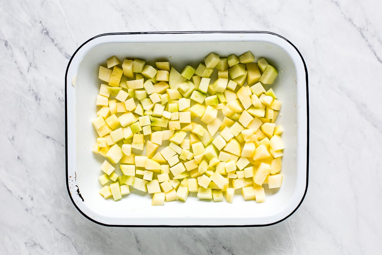 Apple chunks arranged evenly in the bottom of a baking dish.