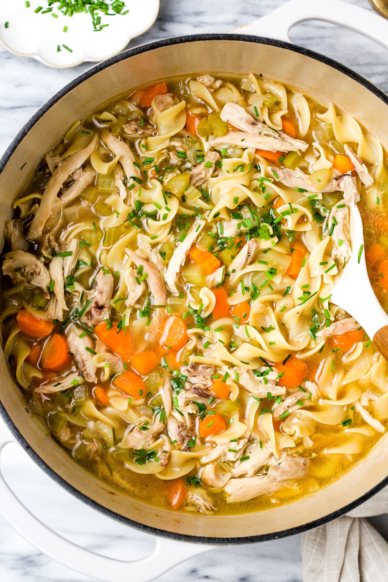 Chicken noodle soup in a large, white pot. 