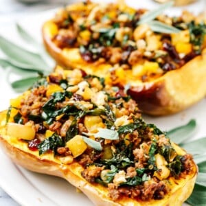 Stuffed butternut squash halves on a white serving plate.