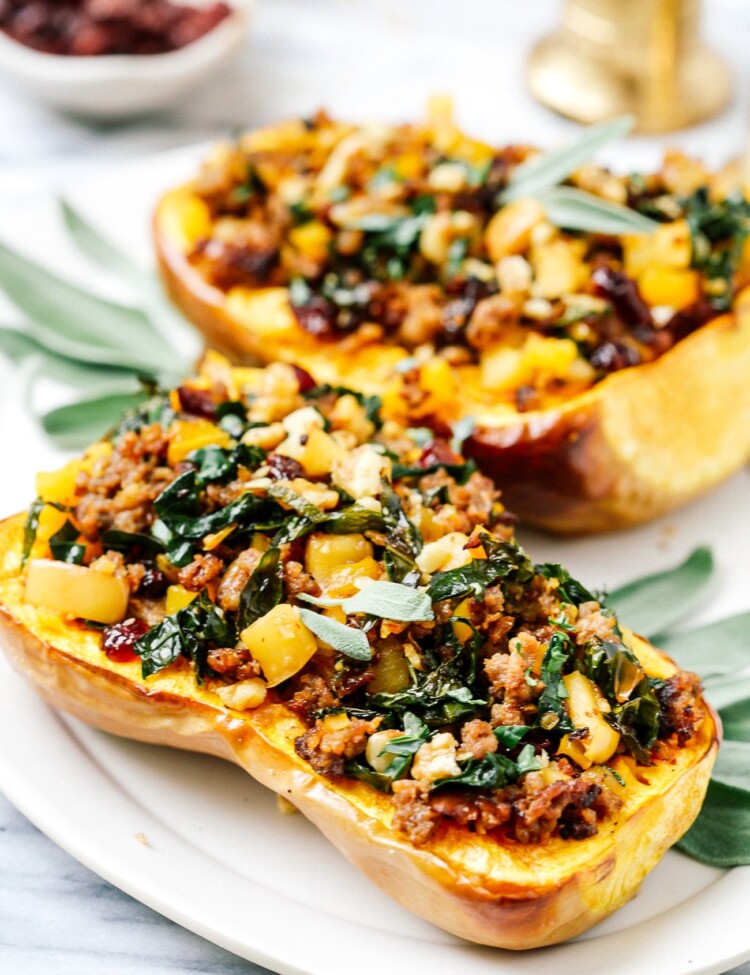 Stuffed butternut squash halves on a white serving plate.