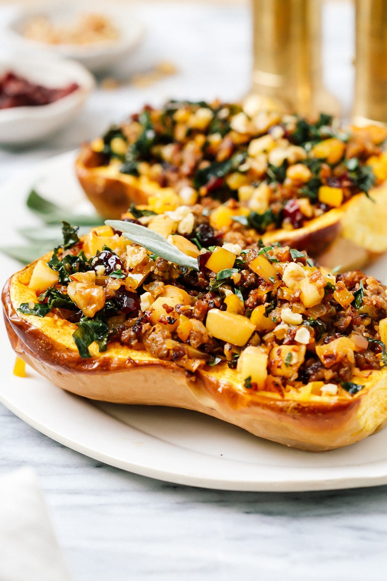 Stuffed butternut squash halves on a white serving plate.