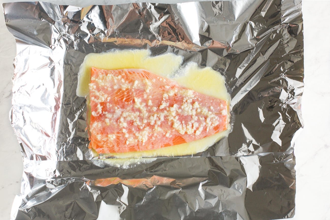 salmon in a baking sheet with melted butter mixture on top 