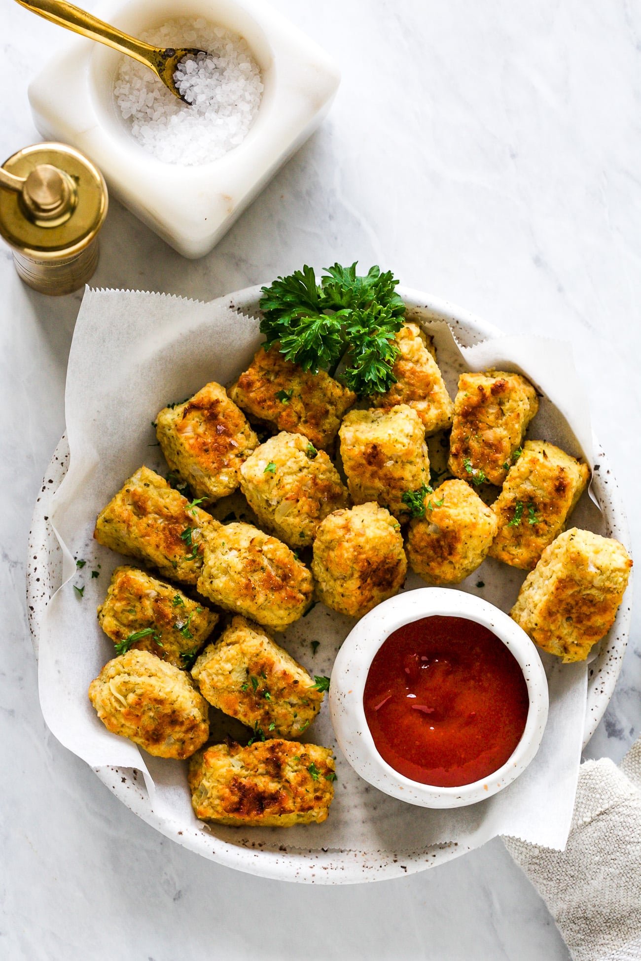 Cauliflower tots in a white serving dish with ketchup.