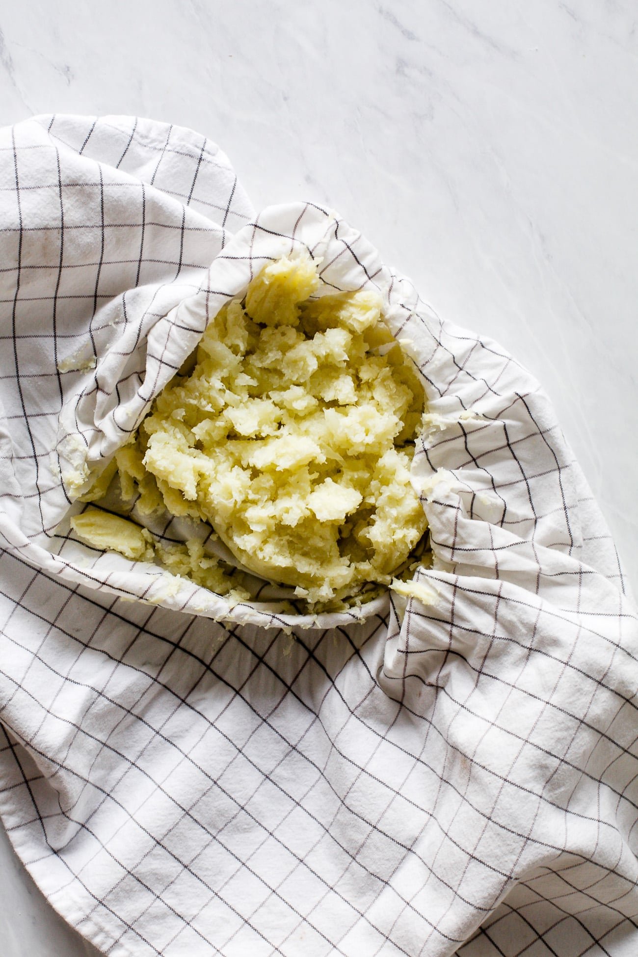 Squeezing excess liquid from pureed cauliflower with kitchen towel. 