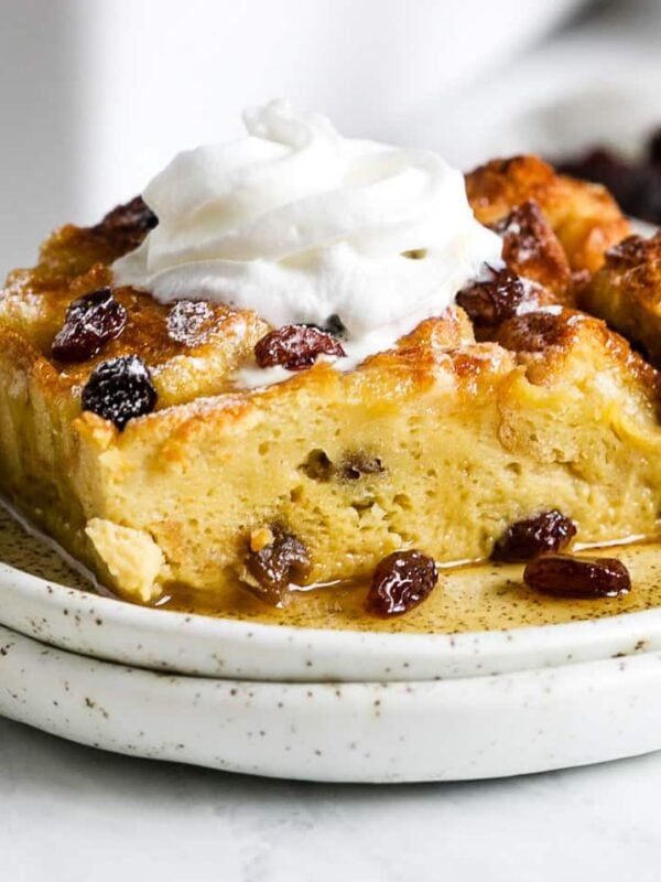A piece of casserole with whipped topping on a small white plate.
