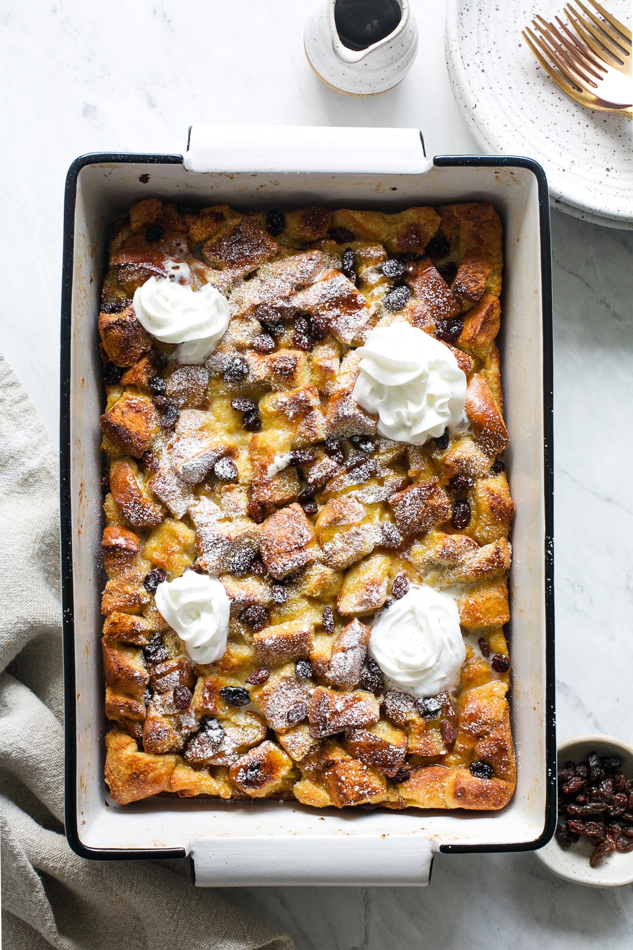 Whole baked french toast casserole with whipped topping and powdered sugar.