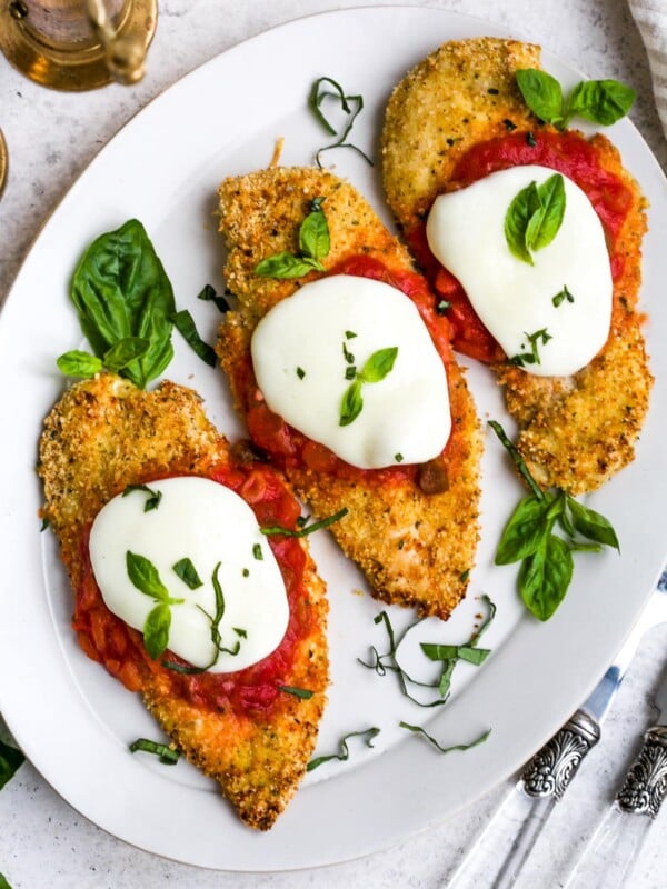 Overhead view of baked chicken parmesan on a white plate