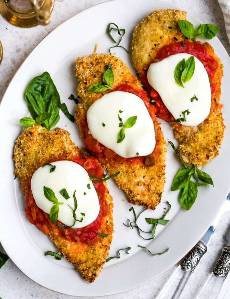 Overhead view of baked chicken parmesan on a white plate