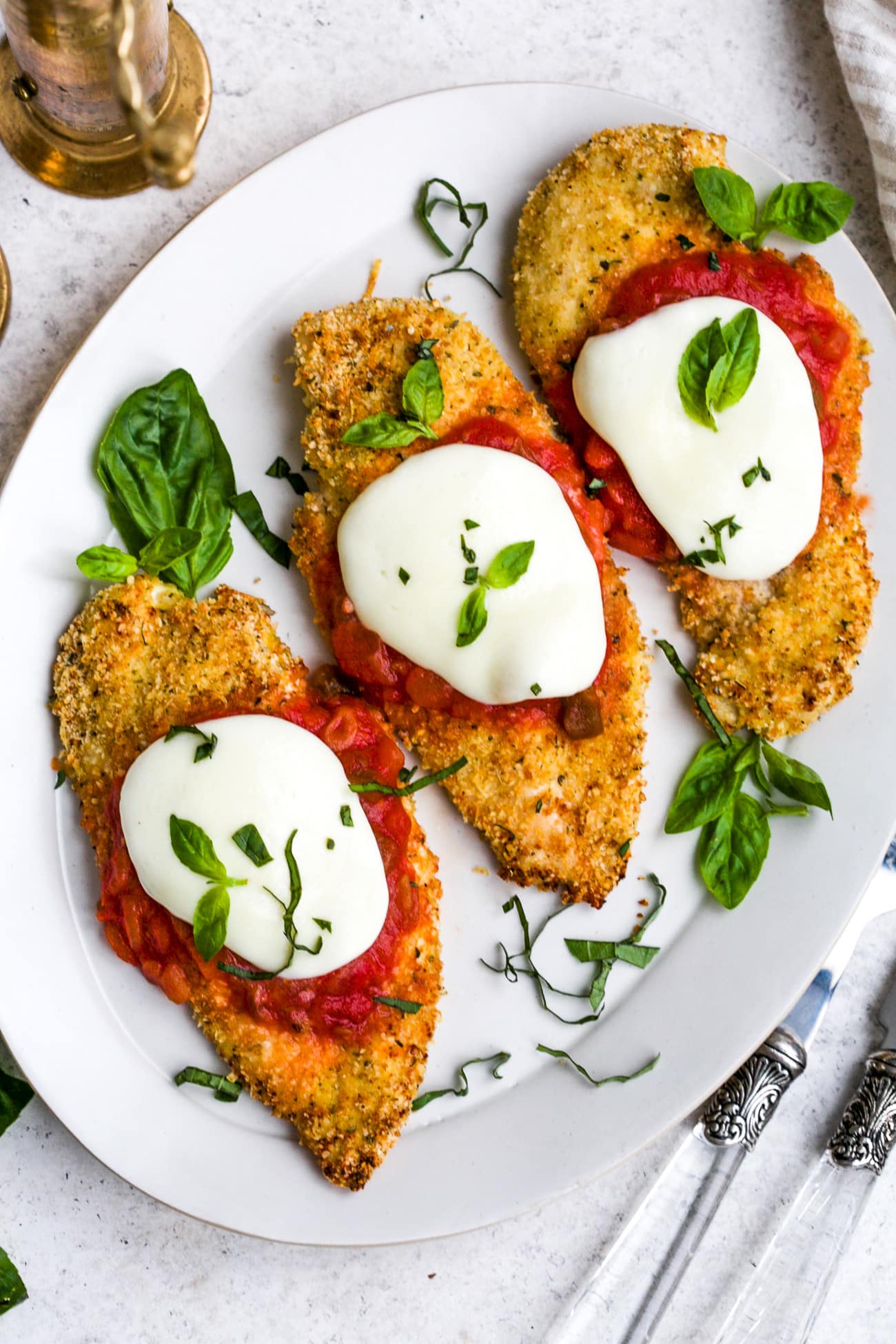 Baked chicken parmesan on a white serving plate.