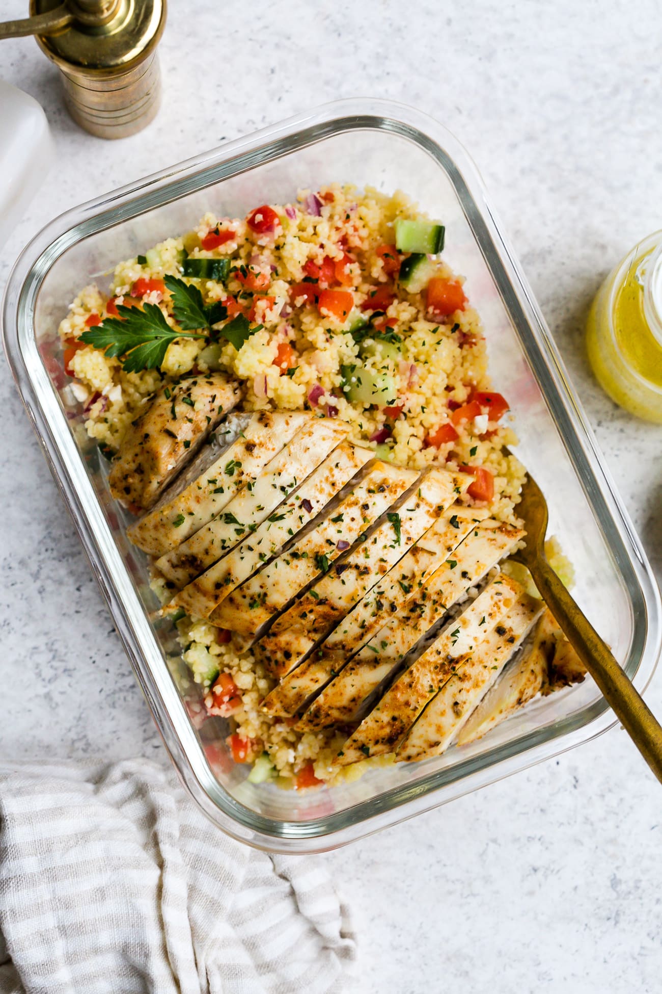 Chicken couscous salad in a small, glass meal-prep container.