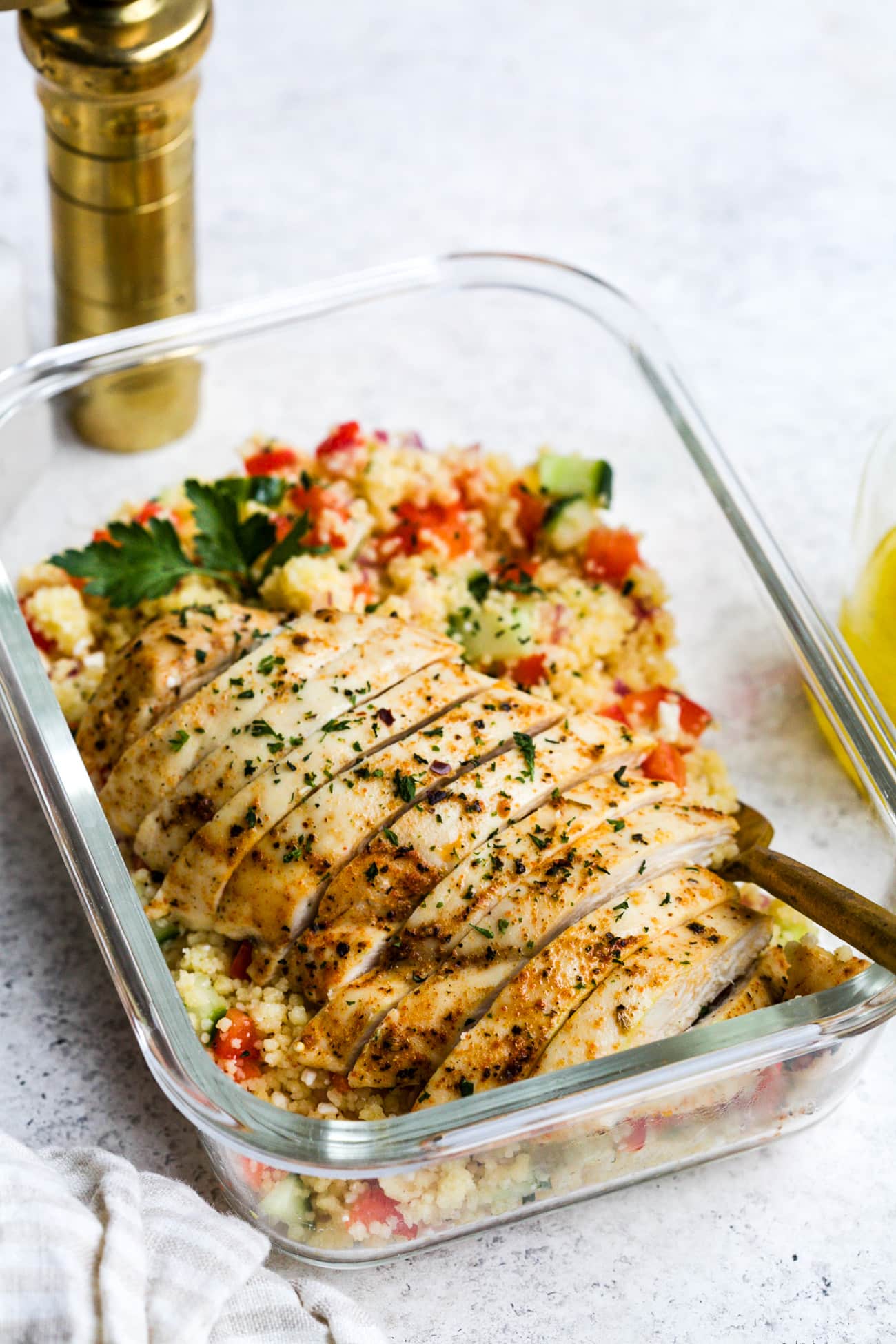 Chicken couscous salad in a small, glass meal-prep container.