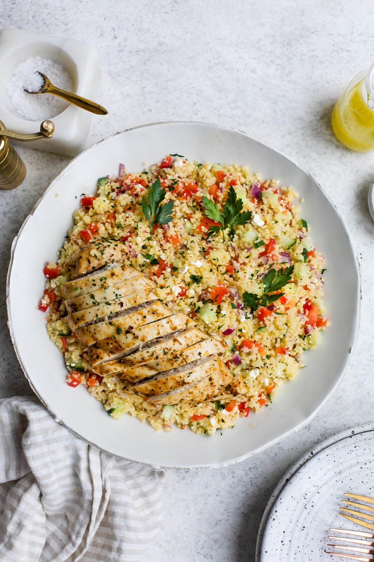 Chicken couscous salad in a large, white serving bowl. 