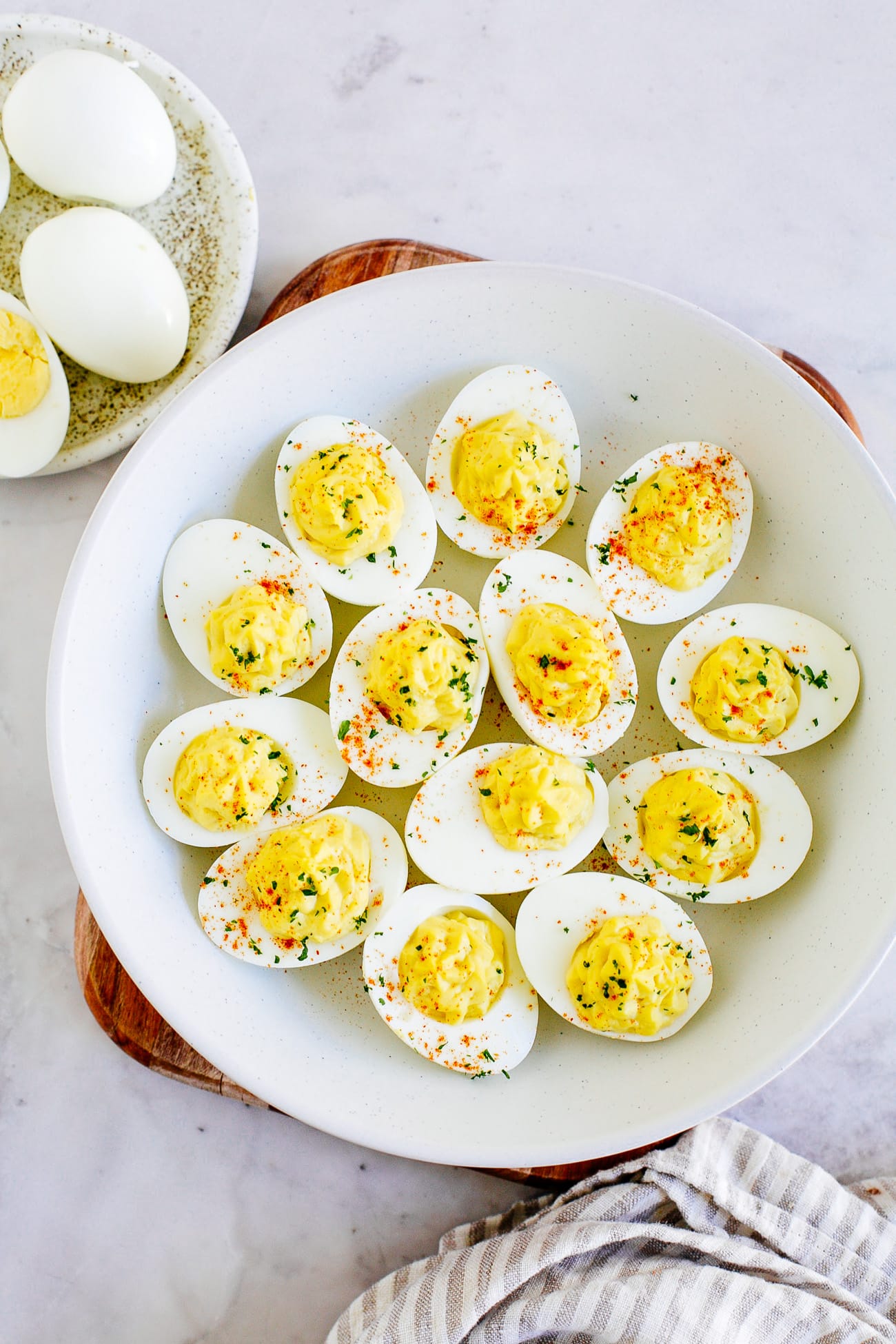 A platter of easy deviled eggs garnished with chives and paprika.
