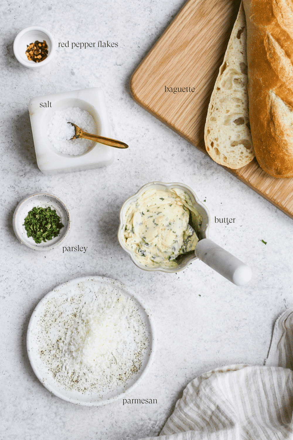Ingredients for garlic bread arranged on a white countertop.