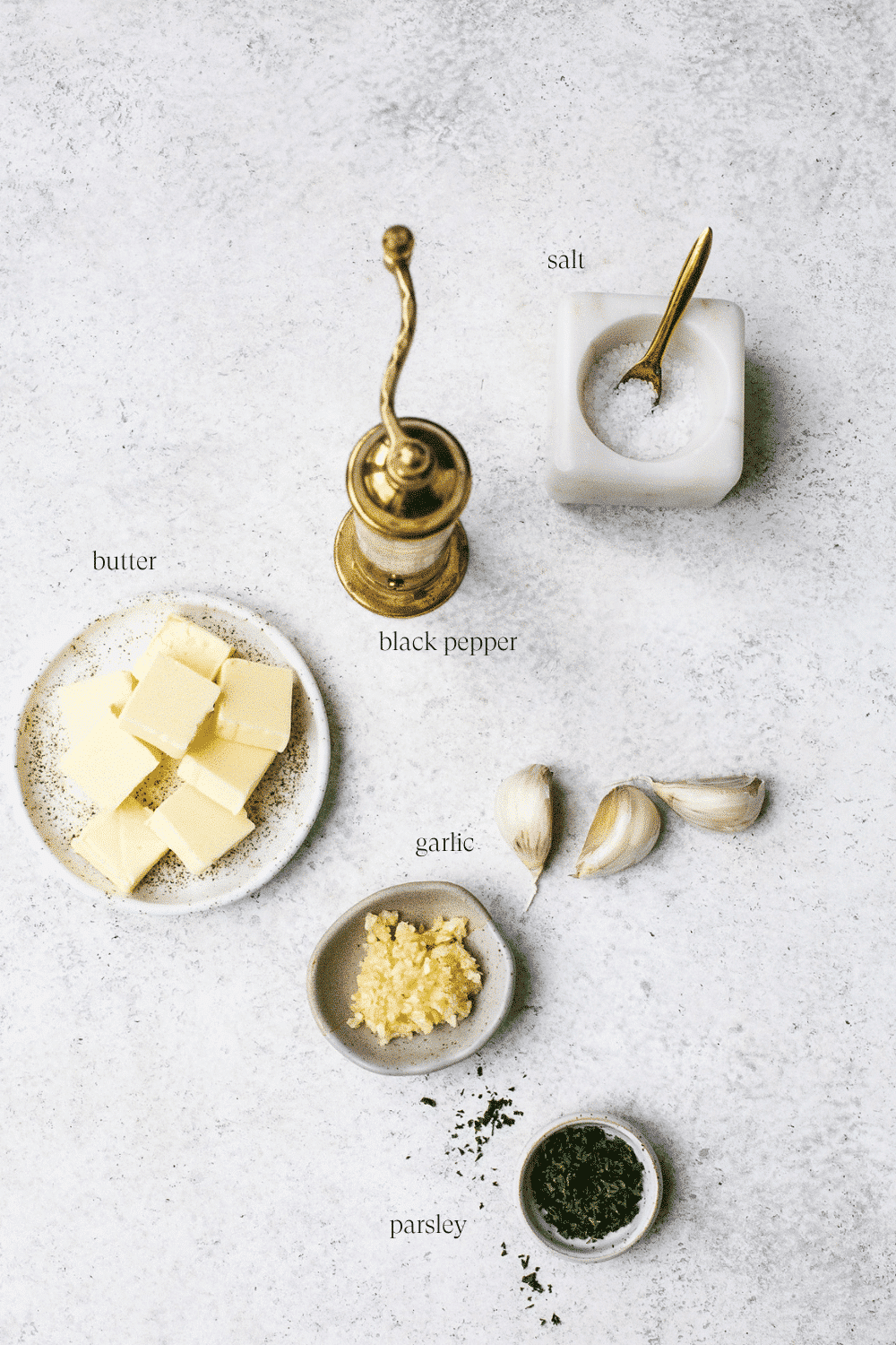 Ingredients for garlic butter arranged on a white countertop. 