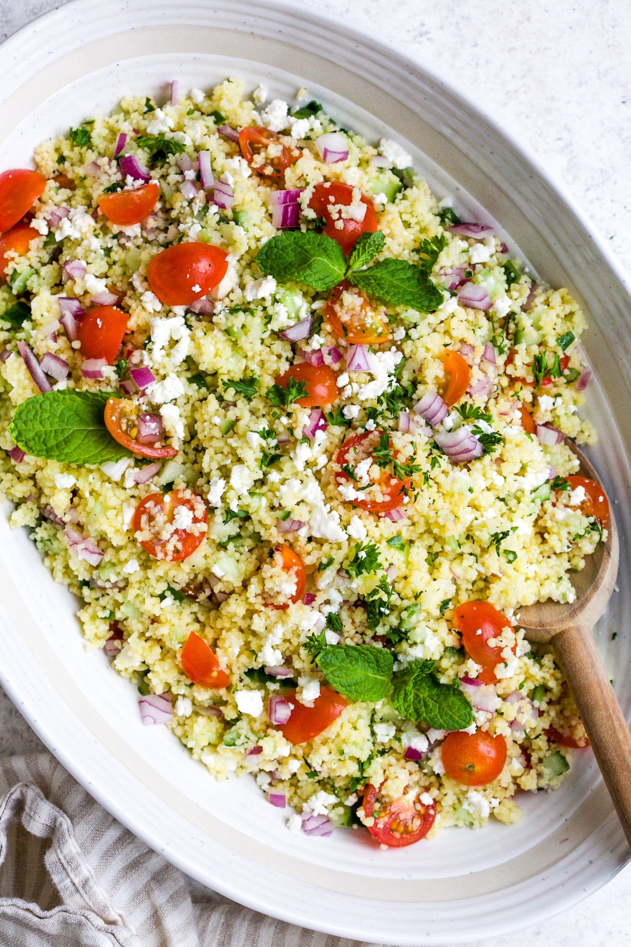 closeup of couscous salad in a white bowl.