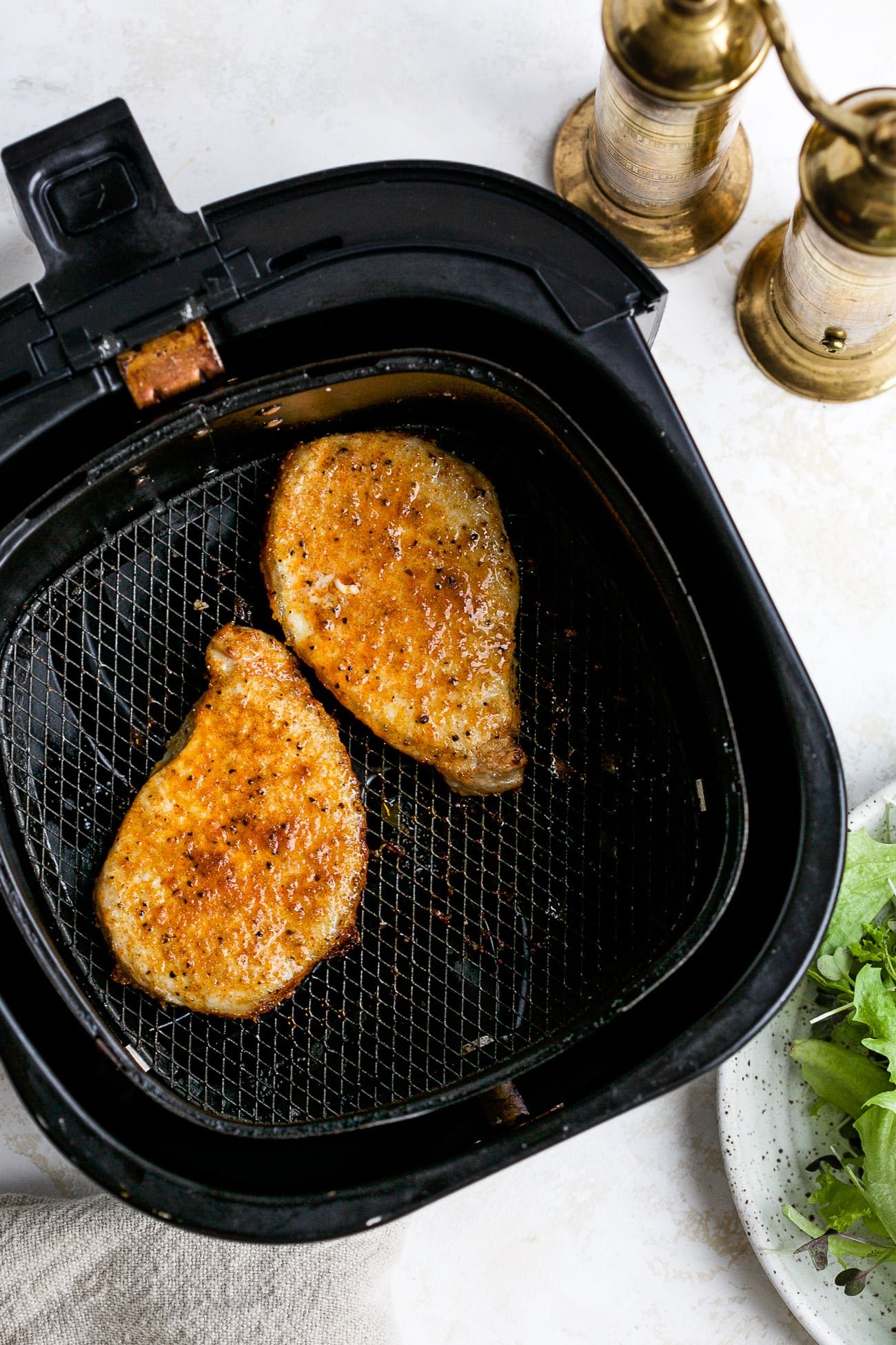 Cooked pork chops in air fryer basket. 