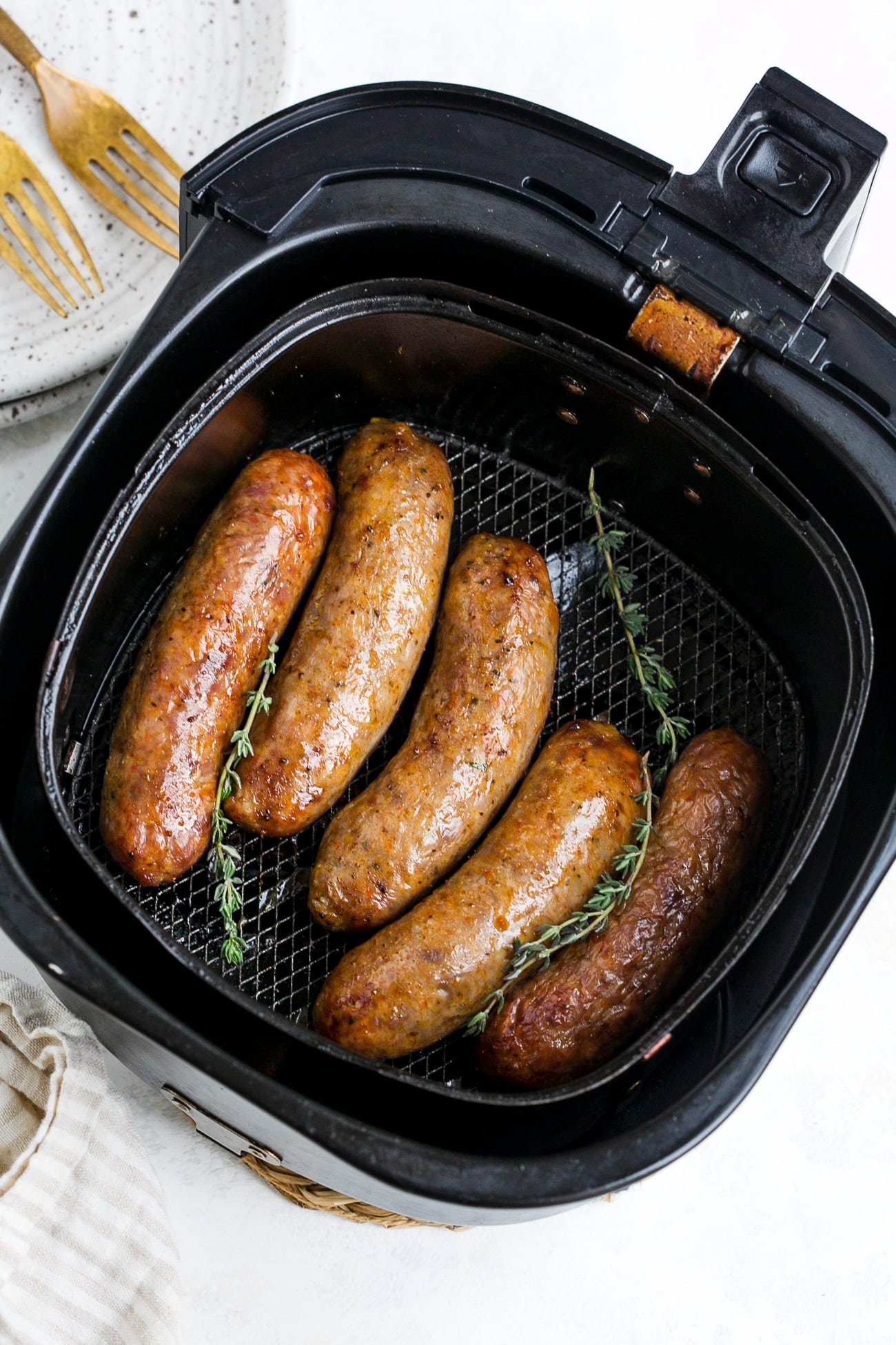 Cooked sausage in air fryer basket.