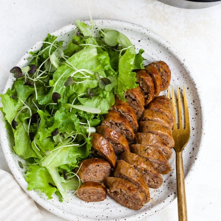 Sliced and plated air fryer sausage with a side salad.
