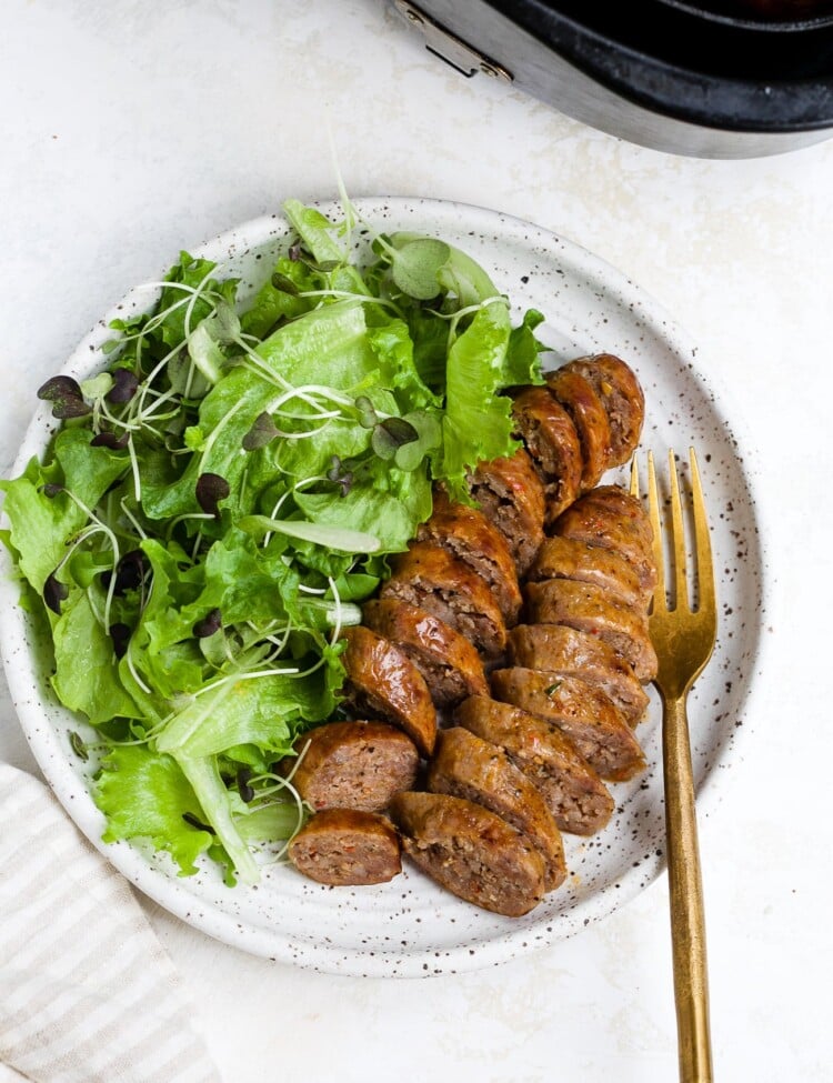 Sliced and plated air fryer sausage with a side salad.