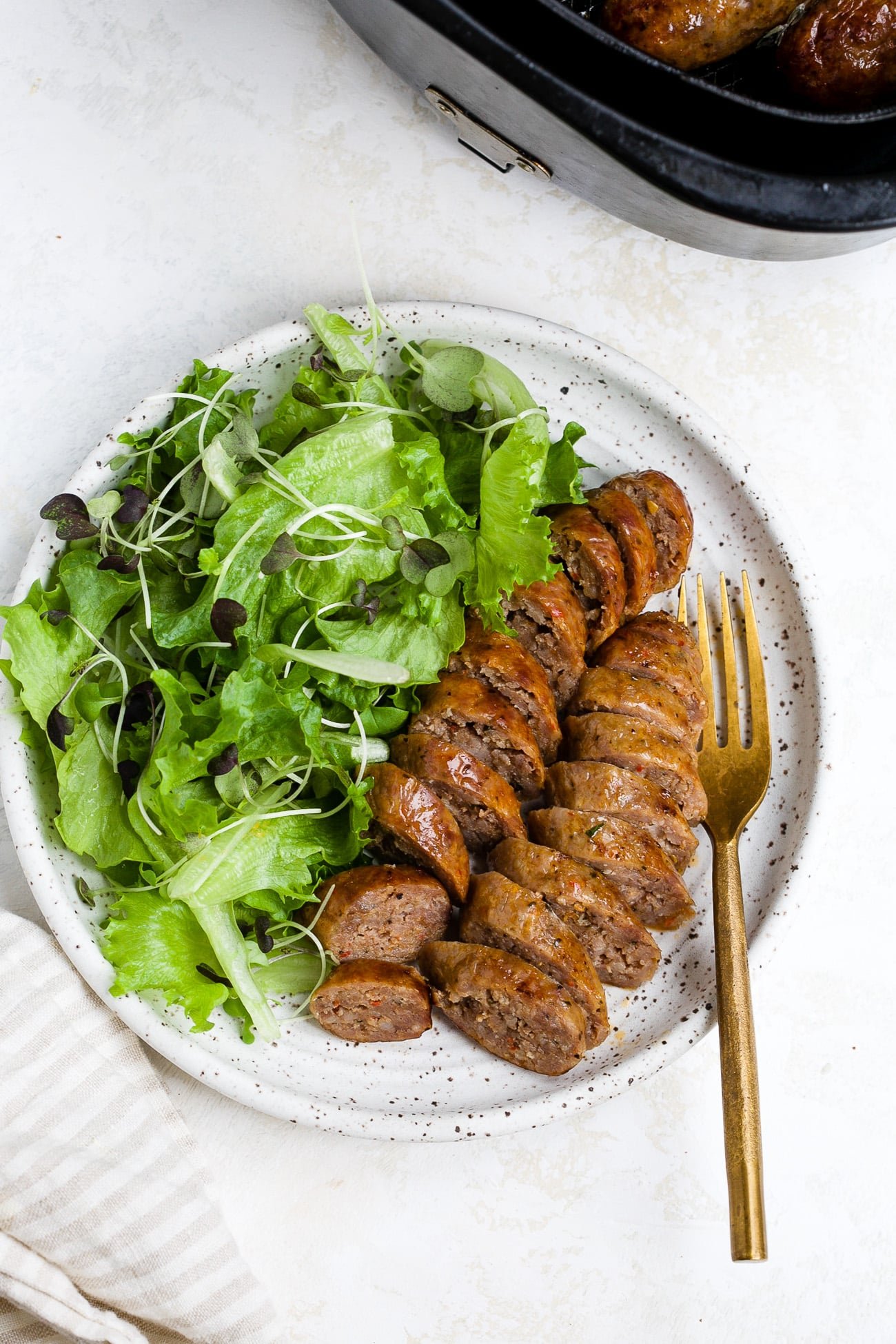 Sliced and plated air fryer sausage with a side salad. 