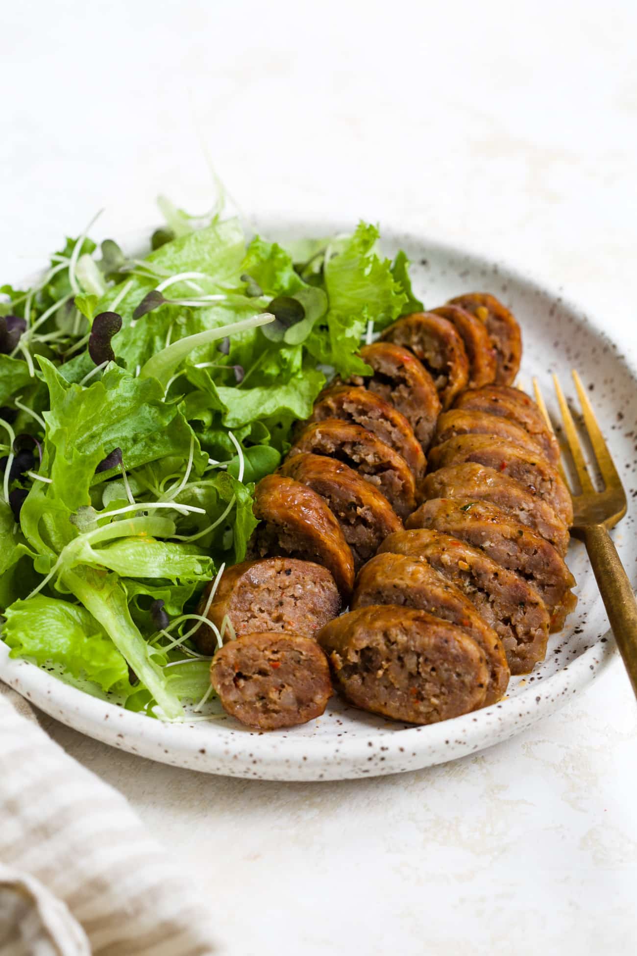Sliced and plated air fryer sausage with a side salad. 