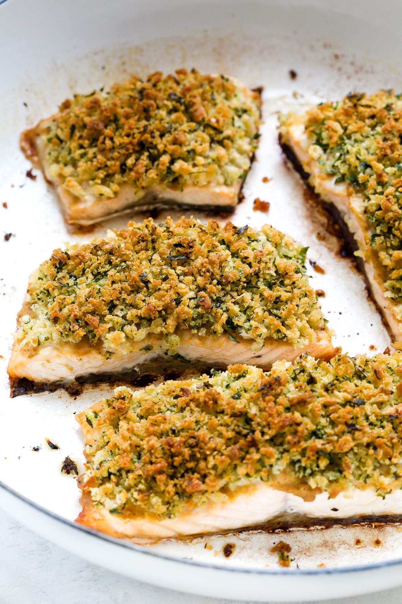 Close up of panko crusted salmon in a white skillet.