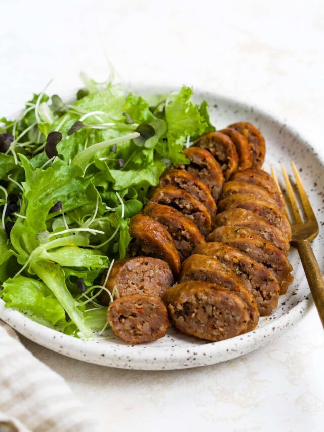 Sliced and plated air fryer sausage with a side salad.