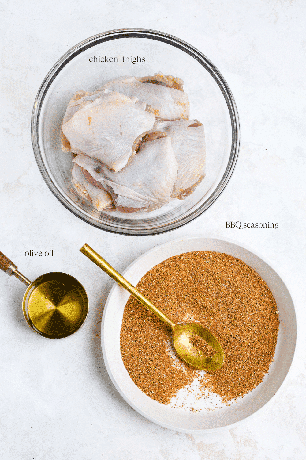 ingredients to make grilled chicken including raw chicken, olive oil, and bbq seasoning on a white plate with a white background