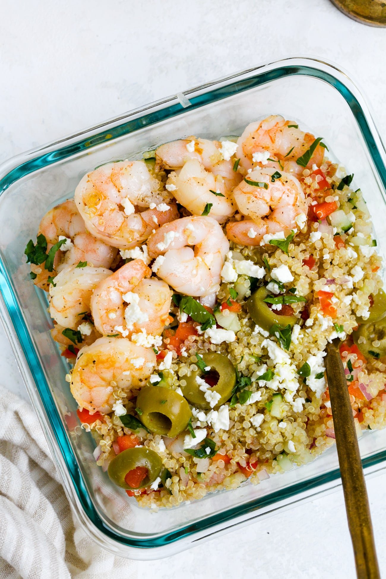 Overhead view of shrimp quinoa salad in a glass meal-prep bowl.