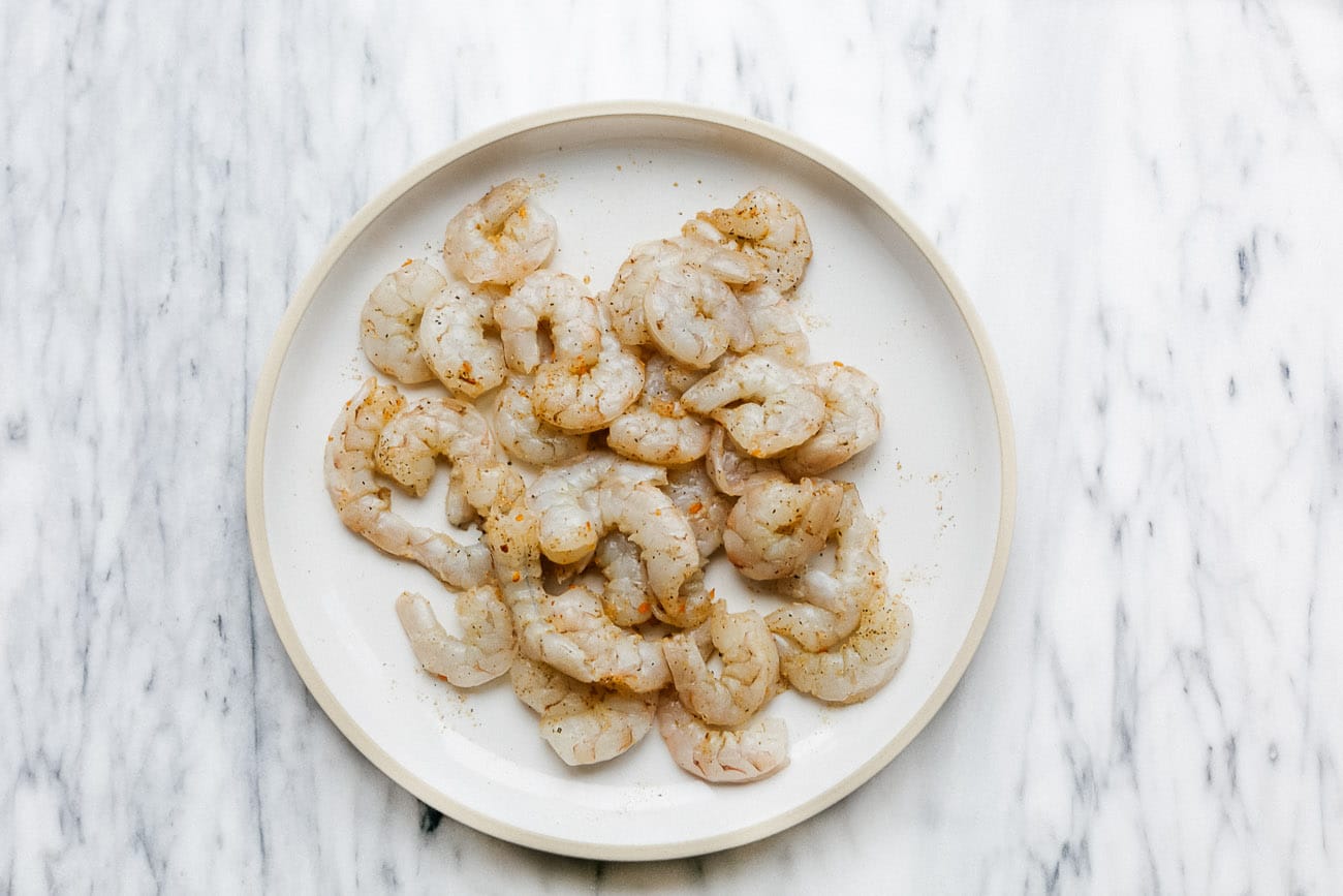 overhead view of raw shrimp on a white plate. 