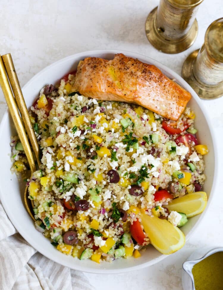 Mediterranean quinoa salad with salmon in a serving bowl.
