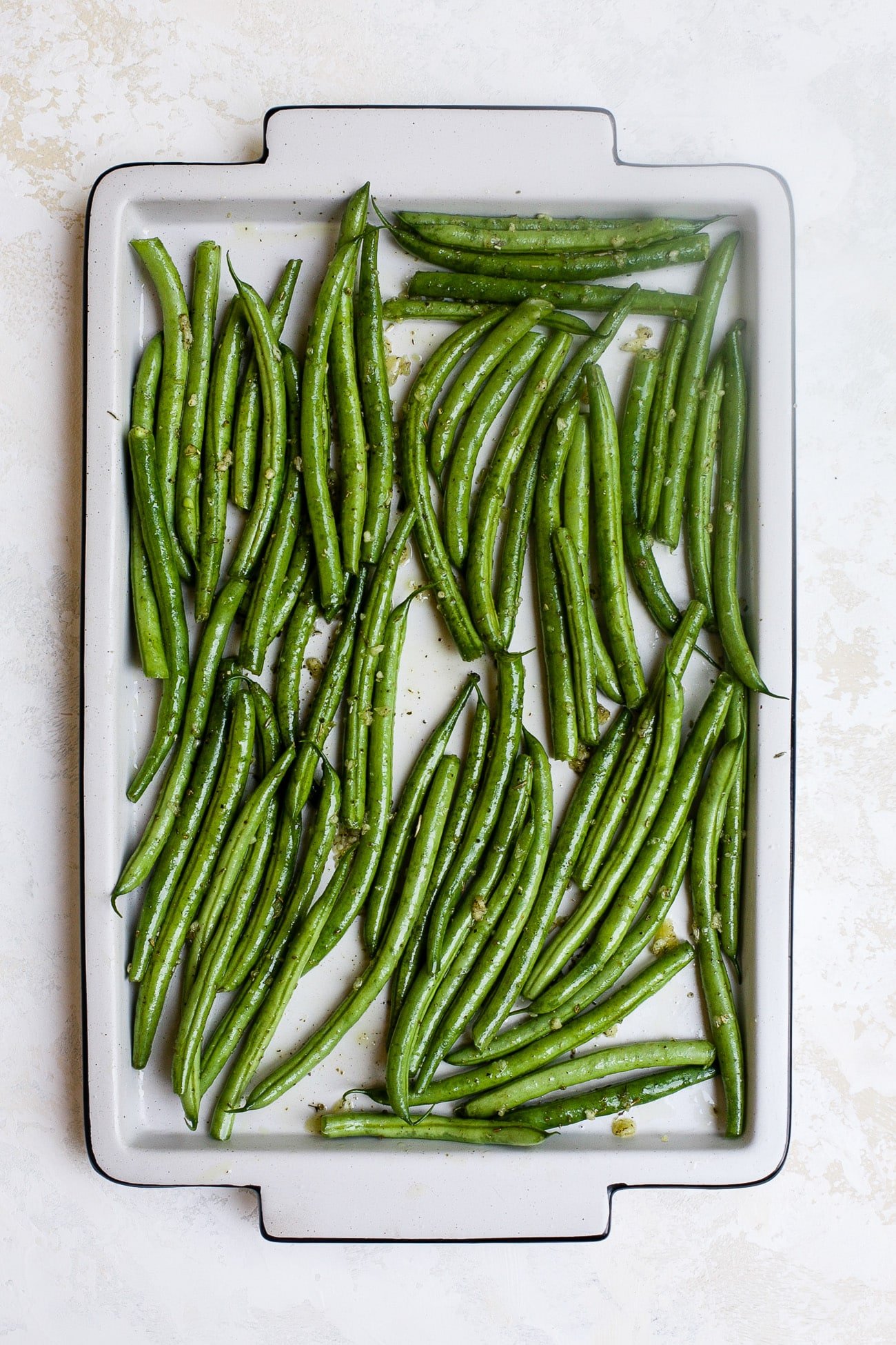 Seasoned green beans on a large baking sheet. 