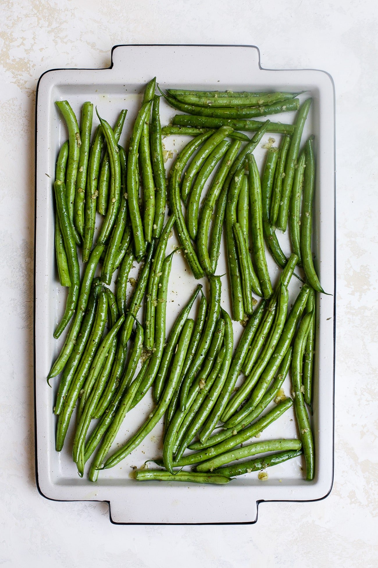 Seasoned green beans on a large baking sheet.