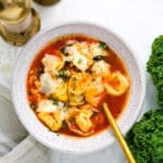 overhead view of tortellini soup in a white bowl.