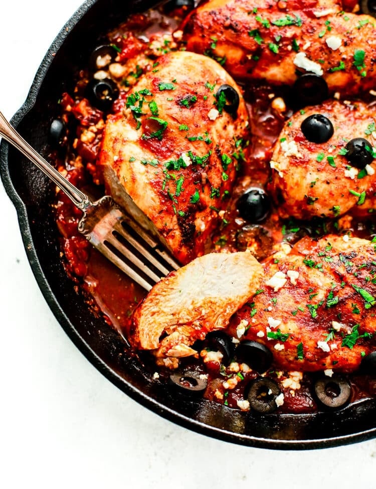 overhead view of a cast iron skillet containing Mediterranean Chicken breast
