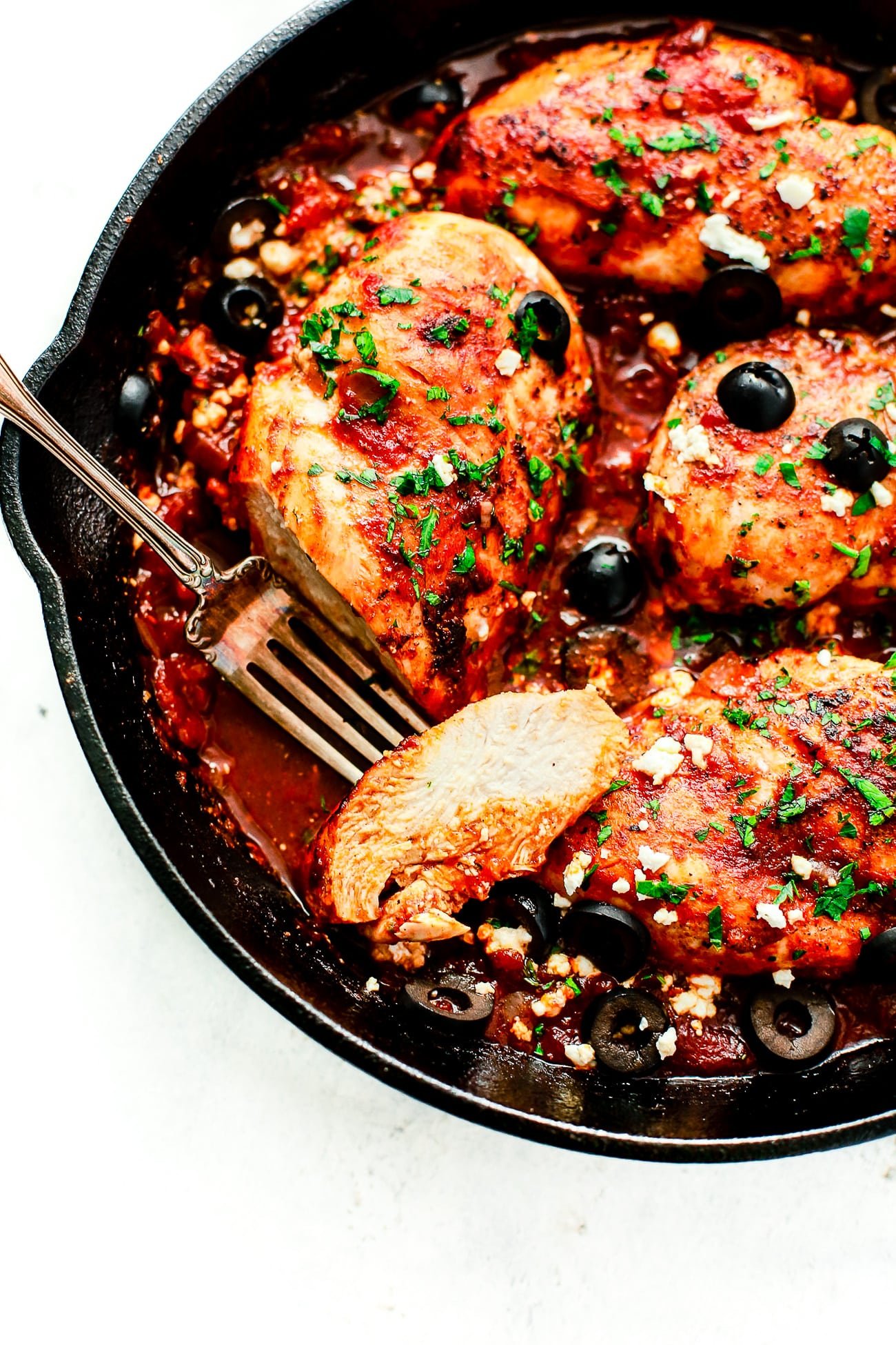 closeup view of a cast iron skillet containing Mediterranean Chicken breast